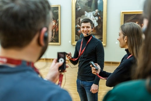 guide with a group of visitors showing art in a museum using OTG
