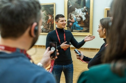 guide with a group of visitors showing art in a museum using OTG audioguide